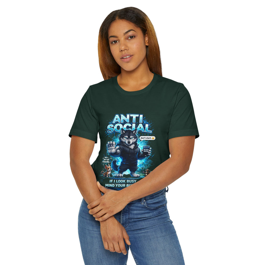A woman with straight brown hair and blue jeans wears the  Anti Social Wolf T-Shirt — a dark green streetwear tee featuring a grumpy wolf graphic and the words “ANTI SOCIAL. If I look busy, mind your business.”.