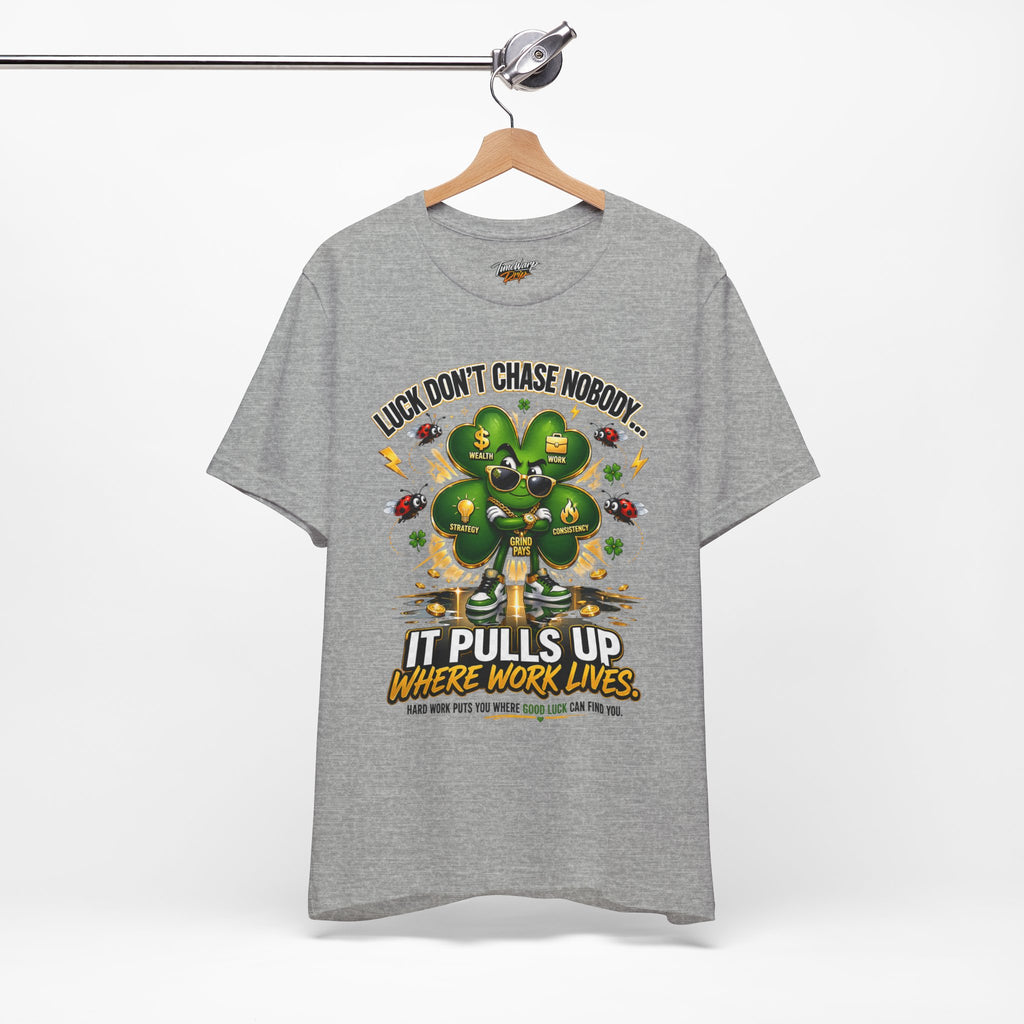 The TimeWarp Drip Lucky Clover "Pulls Up Lives" Graphic T-Shirt in gray (sizes S–3XL) features a suited man, clover with money symbols, and the saying: "Luck don’t chase nobody – it pulls up where work lives. Hard work attracts good luck.