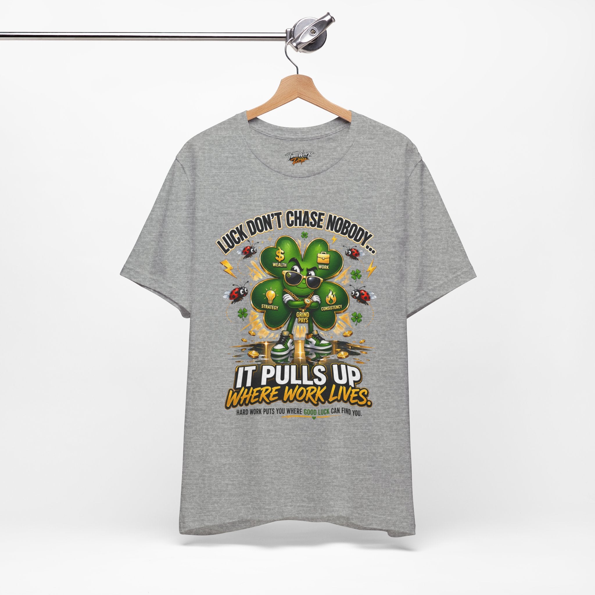 The TimeWarp Drip Lucky Clover "Pulls Up Lives" Graphic T-Shirt in gray (sizes S–3XL) features a suited man, clover with money symbols, and the saying: "Luck don’t chase nobody – it pulls up where work lives. Hard work attracts good luck.