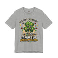The Lucky Clover "Pulls Up Lives" Graphic T-Shirt in gray (S-3XL) features a four-leaf clover with sunglasses, coins, and ladybugs alongside the quote: Luck don’t chase nobody… it pulls up where work lives. Hard work puts you where luck finds you.