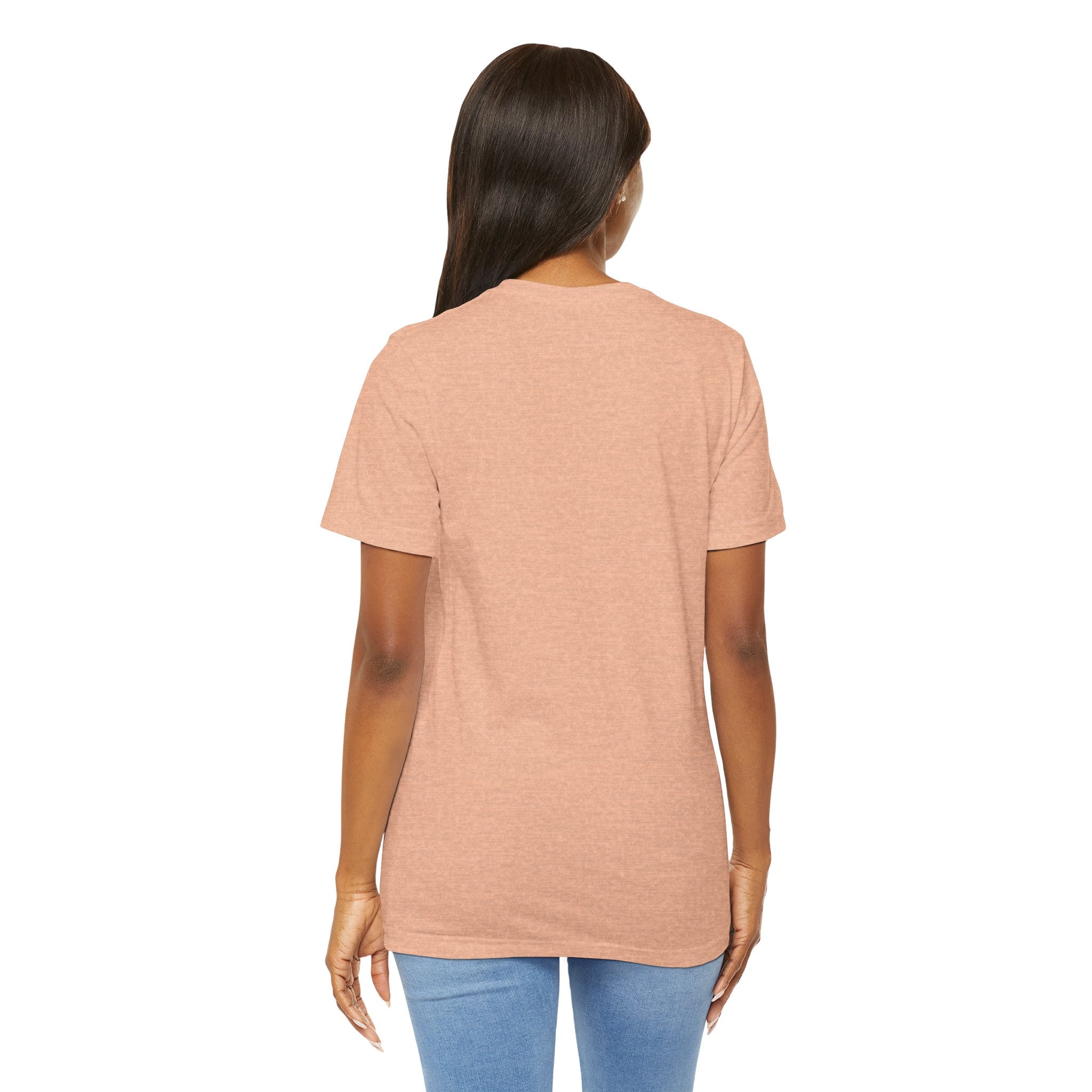 A woman with long dark hair stands with her back to the camera wearing the Lucky Clover "Pulls Up Lives" Graphic T-Shirt by TimeWarp Drip in light brown and light blue jeans. The t-shirt comes in sizes S, M, L, and XL against a white background.