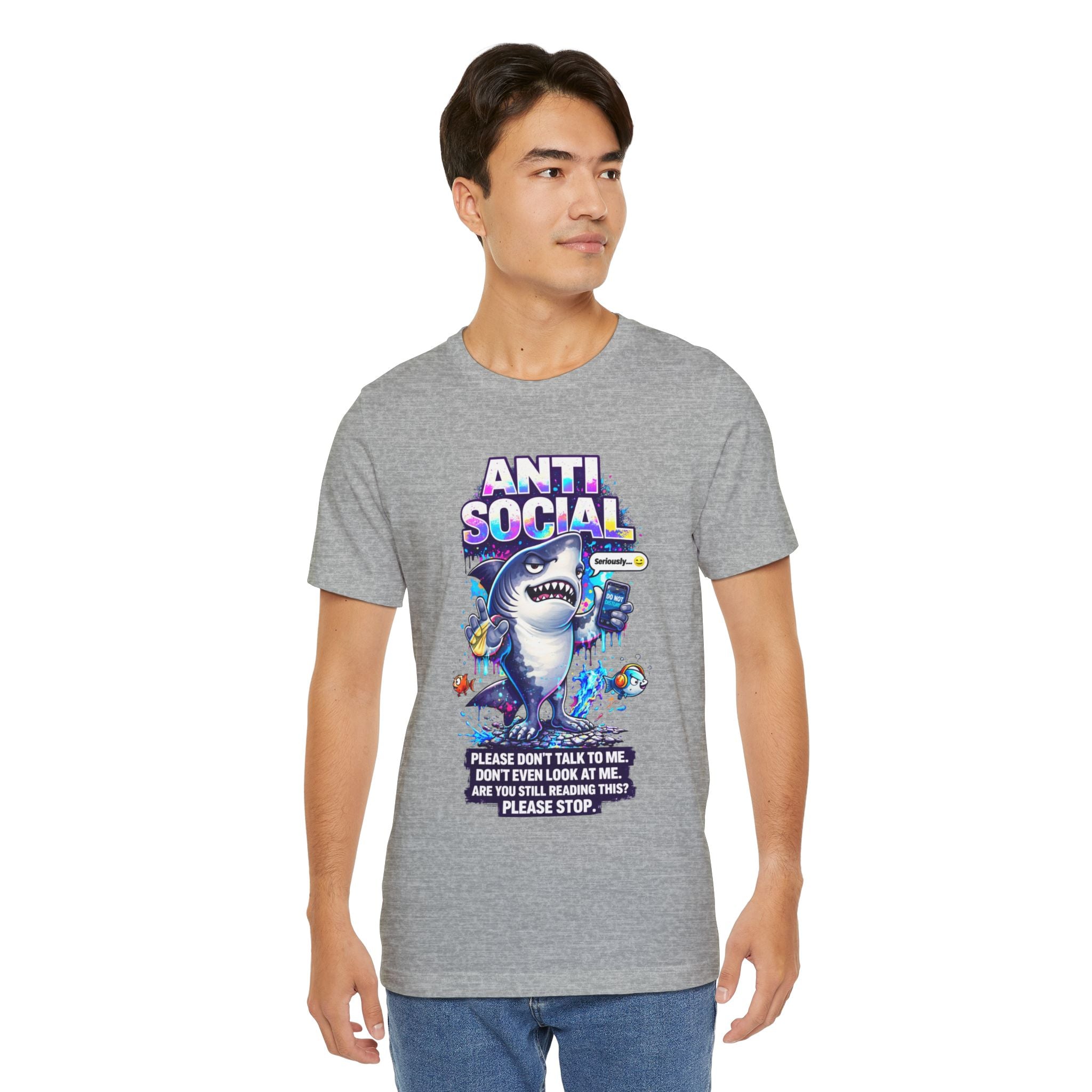 A young man wears the Anti Social Shark T-Shirt — Funny Introvert Graphic Tee, featuring a cartoon shark and colorful sea creatures on soft unisex cotton. The shirt reads: ANTI SOCIAL and Please don’t talk to me, don’t even look at me.
