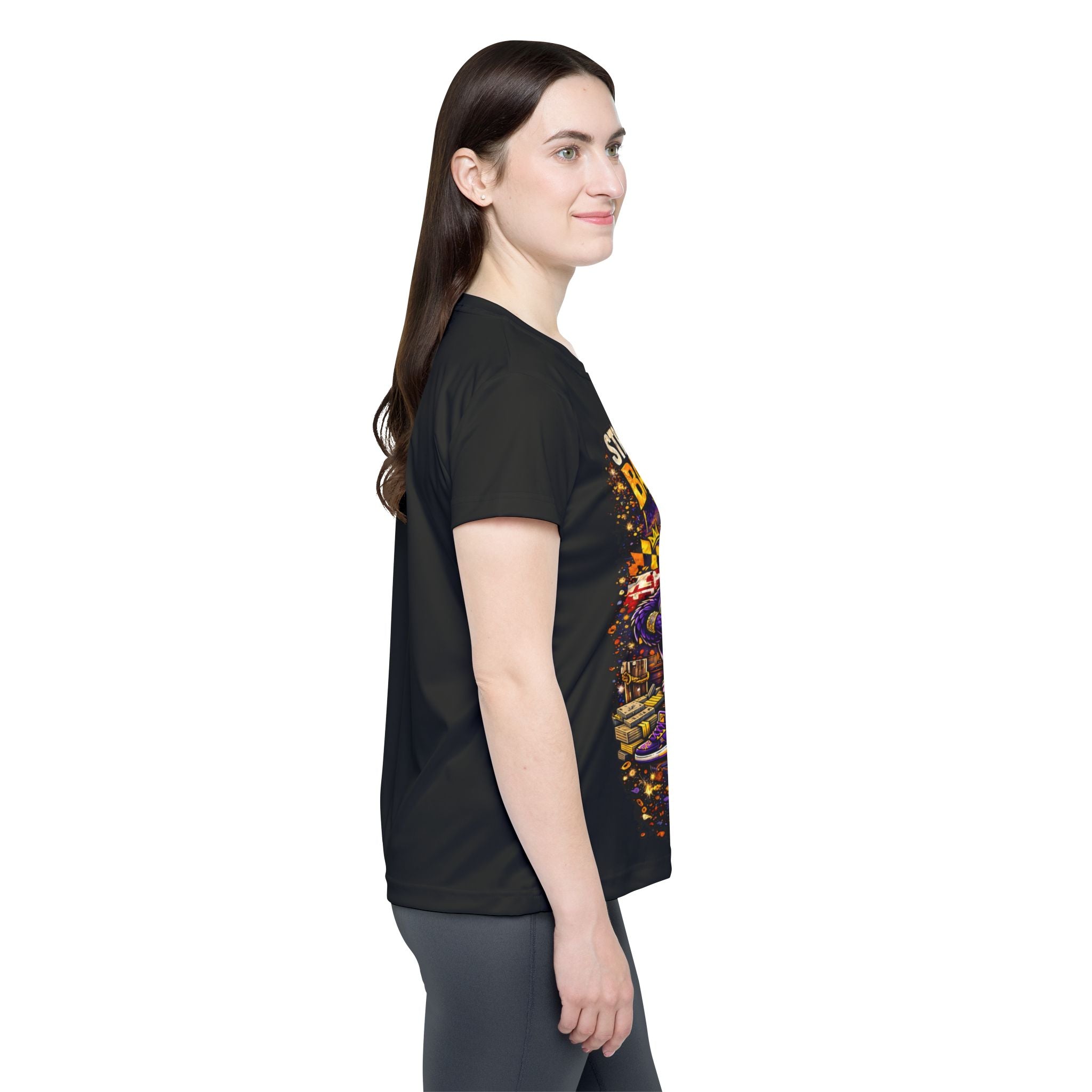 A woman with long brown hair stands in profile, smiling and wearing the TimeWarp Drip Straight Outta Baltimore Women's Sports Jersey, a black Charm City fan tee, paired with gray pants against a plain white background.