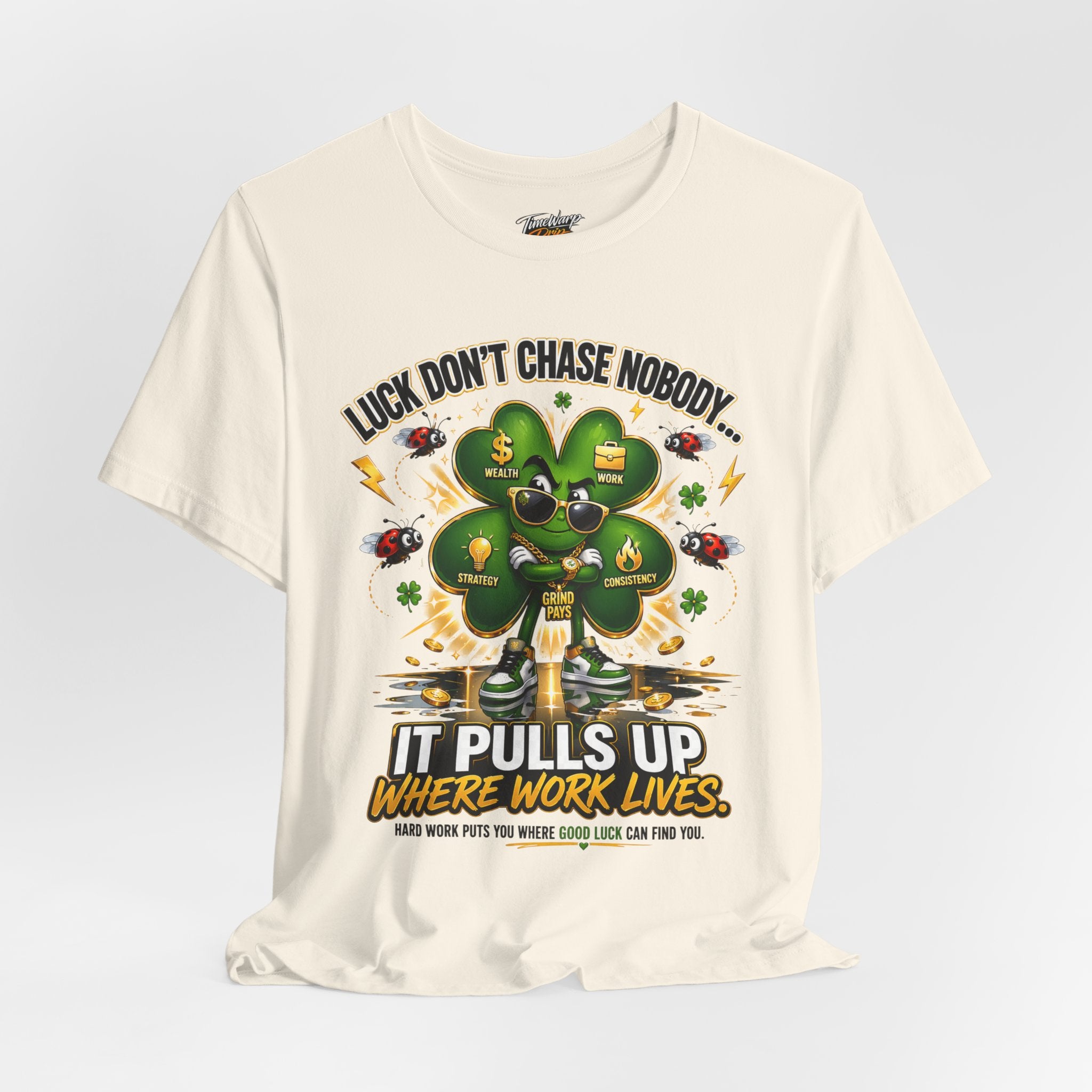The TimeWarp Drip "Lucky Clover, Pulls Up Lives" Graphic T-Shirt features a stylish clover with sunglasses and gold chains. Available in S-3XL, it reads: “Luck don’t chase nobody! It pulls up where work lives. Hard work puts you where good luck can find you.”.