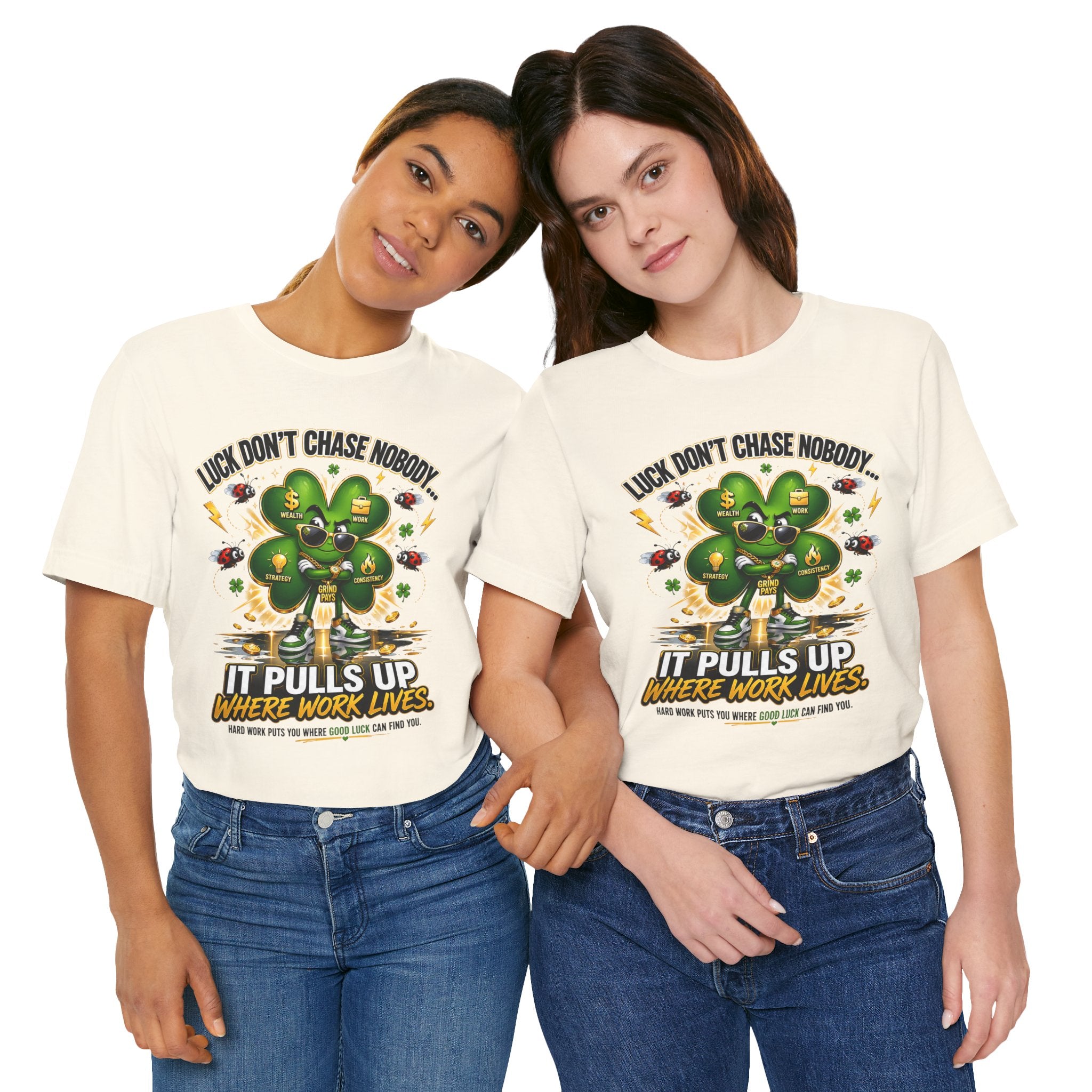 Two women smile and hold hands, wearing TimeWarp Drip's Lucky Clover "Pulls Up Lives" Graphic T-Shirt (sizes S–3XL). Each white tee features a four-leaf clover and the phrase, “Luck doesn’t chase nobody. It pulls up where work lives.”.