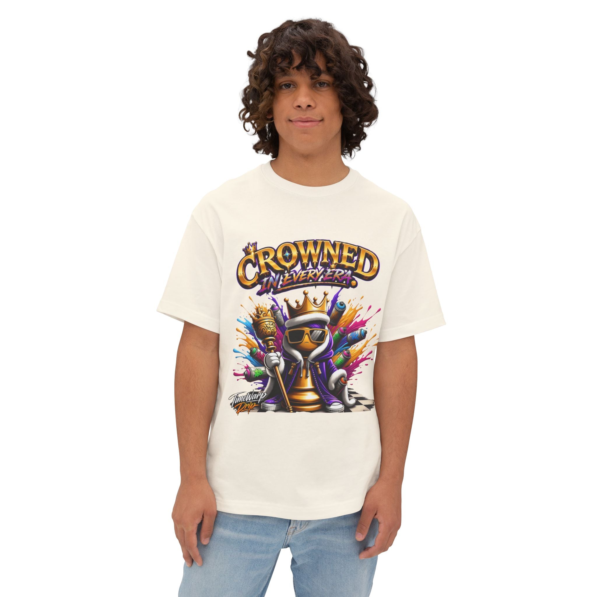 A young person with curly hair wears the "Crowned In Every Era - Unisex Oversized Boxy Tee," a relaxed fit white shirt with a colorful crowned chess piece graphic and the text “CROWNED IN EVERY ERA,” standing against a plain white background.