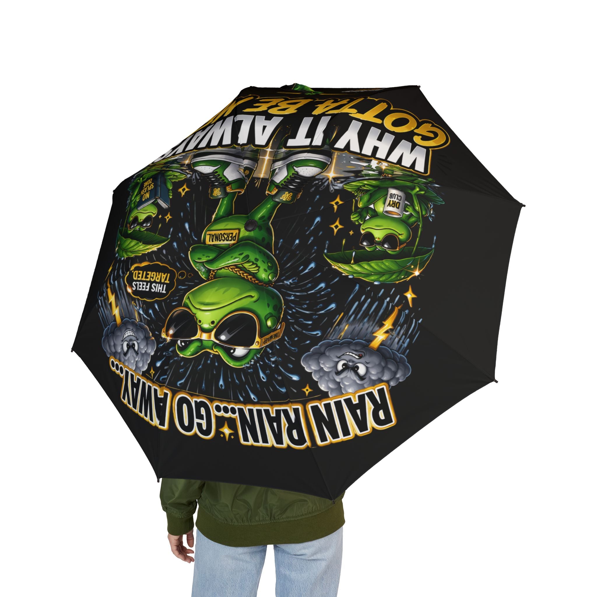 A person holds the Foldable Umbrella — 'Rain? Go Away' Frog Cartoon Waterproof (Black) Travel Umbrella by Printify, open to show its playful frog and text design facing upward.