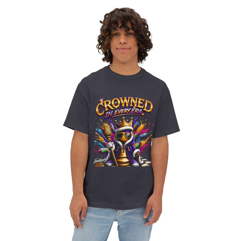 A young person with curly hair wears the "Crowned In Every Era - Unisex Oversized Boxy Tee," made from airlume combed cotton, featuring a colorful crowned chess piece, painter’s brush, and the phrase "Crowned in Every Era" on a white background.