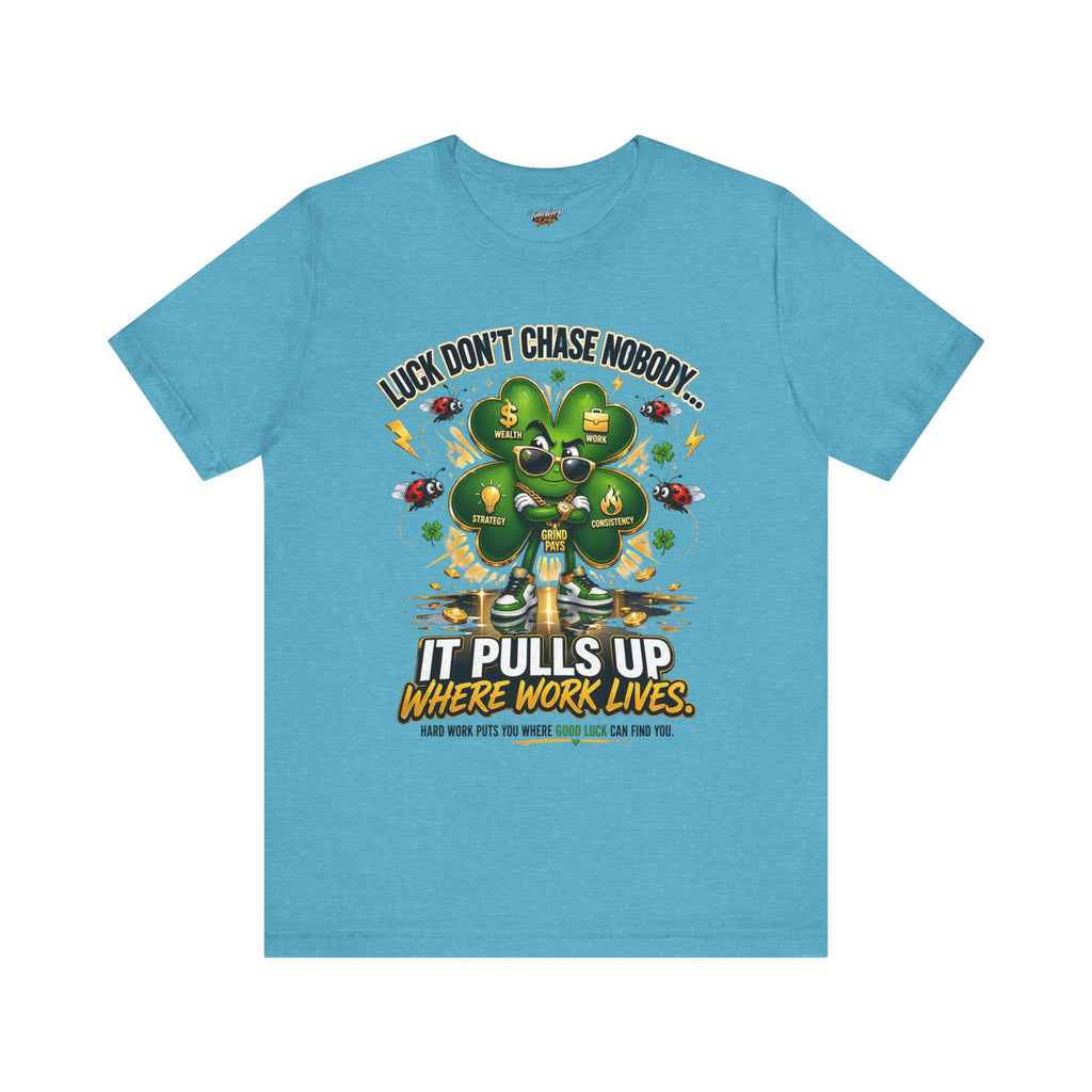 The TimeWarp Drip Lucky Clover "Pulls Up Lives" Graphic T-Shirt comes in light blue (sizes S–3XL) and features cartoon ants, a four-leaf clover, and the motivational quote: “Luck Don’t Chase Nobody... It Pulls Up Where Work Lives.”.
