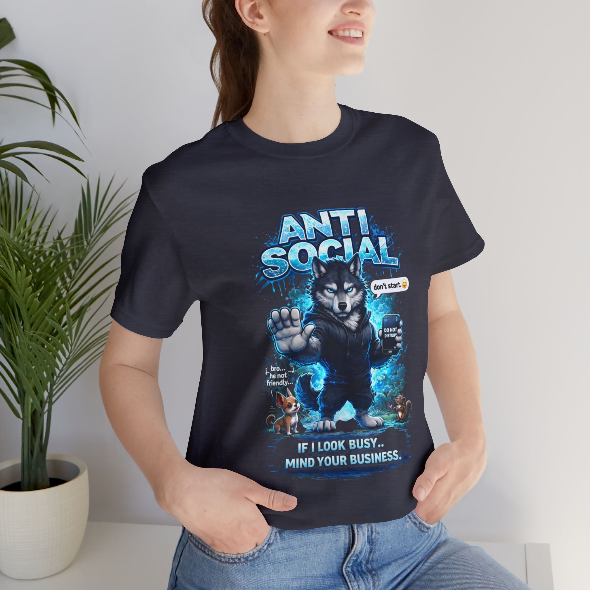 A smiling person wears the Timewarp Drip Anti Social Wolf T-Shirt — Funny Introvert Graphic Tee, featuring a grumpy wolf with a phone, blue effects, and animals, with the text: If I look busy, mind your business. Don't stare.
