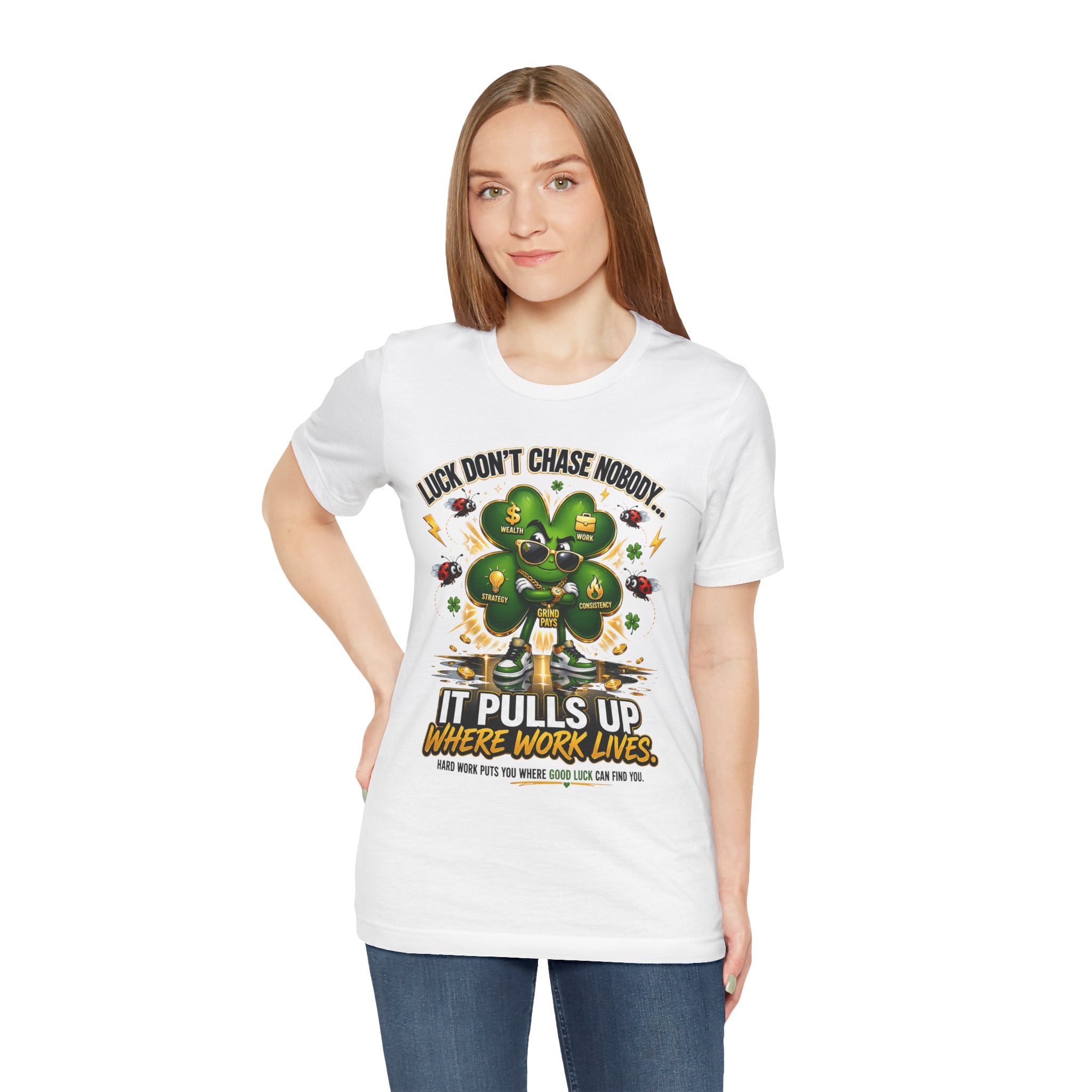 A woman with straight, light brown hair wears theTimeWarp Drip Lucky Clover "Pulls Up Lives" Graphic T-Shirt (sizes S-3XL), featuring a large green four-leaf clover, dollar signs, and the words: Lucky don’t chase nobody. She stands facing forward and smiles.