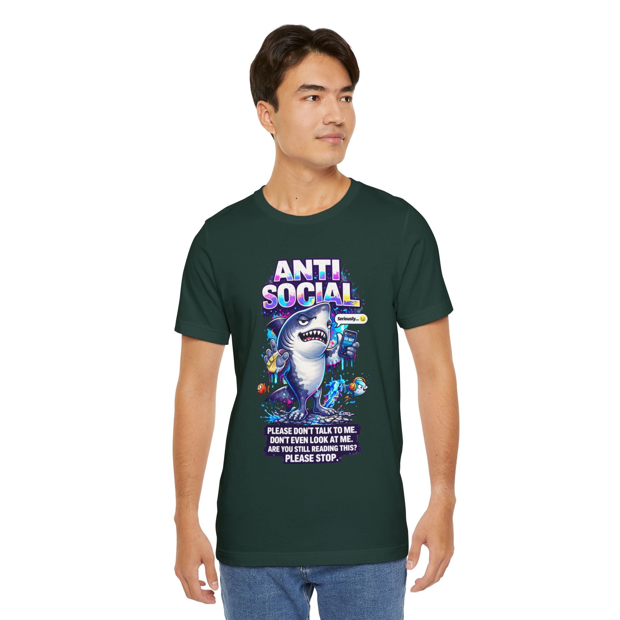 A young man wears the Anti Social Shark T-Shirt — Funny Introvert Graphic Tee, featuring a cartoon shark, colorful sea creatures, and the phrases: ANTI-SOCIAL and “Please don’t talk to me. Don’t even look at me. Are you still reading this? Please stop.”.