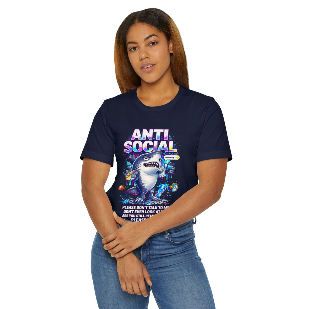 A woman with straight brown hair stands confidently, arms crossed, in the Anti Social Shark T-Shirt — Funny Introvert Graphic Tee, a quirky unisex cotton shirt featuring a cartoon shark and the text "ANTI SOCIAL.