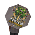 A person holds the Lucky Clover "Pulls Up Lives" Graphic (Grey) Foldable Umbrella, featuring a cartoon shamrock in sneakers with coins and lightning. Motivational graphics pop on gray; one size fits all with an optimal canopy diameter for any occasion.