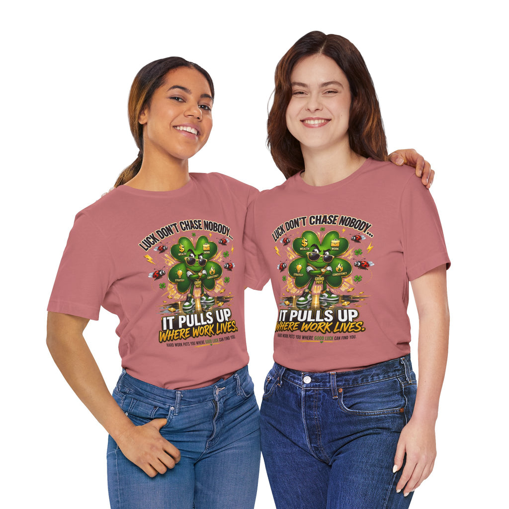 Two women wear TimeWarp Drip’s Lucky Clover "Pulls Up Lives" Graphic T-Shirts, available in sizes S-3XL, featuring a green plant and the phrase "Luck Don’t Chase Nobody. It Pulls Up Where Work Lives," smiling side by side against a white background.