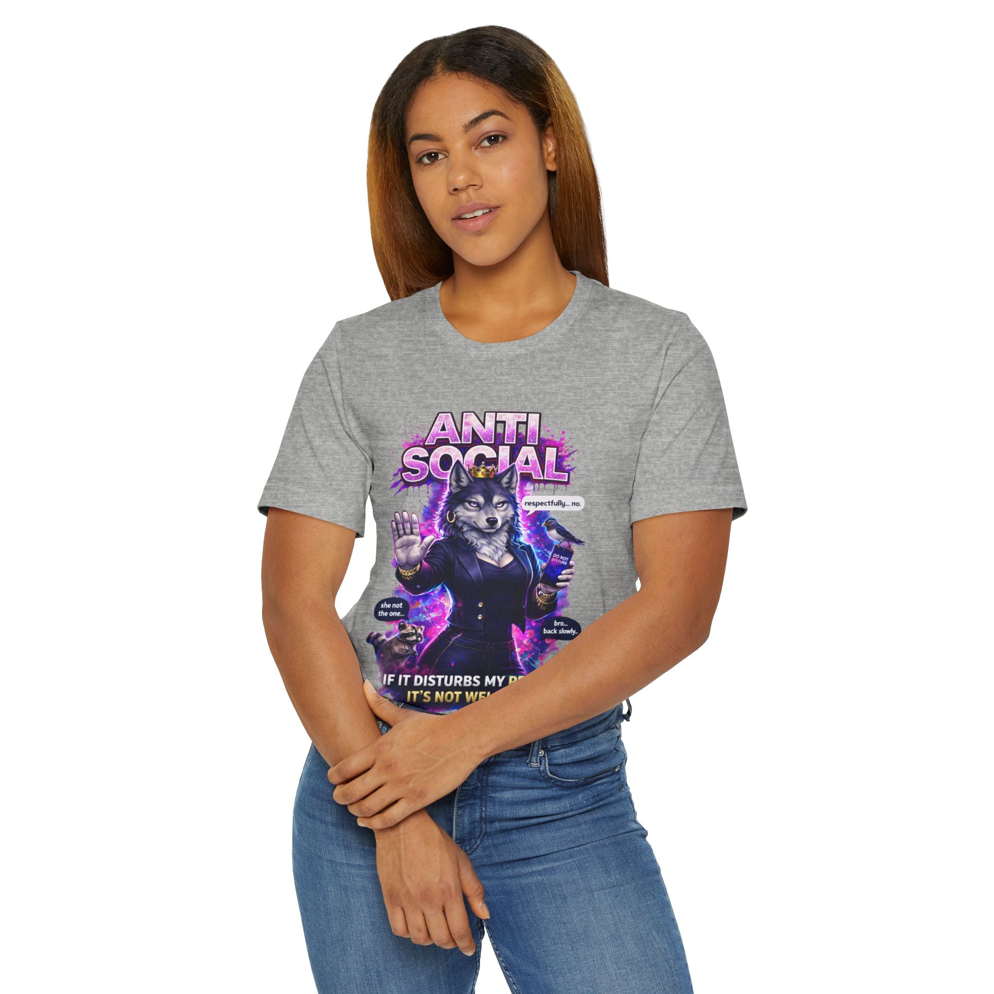 A woman with long hair, arms crossed, stands before a plain background wearing the Anti Social She-Wolf T-Shirt— a gray funny introvert graphic tee featuring “ANTI SOCIAL” and a snarky she-wolf illustration.