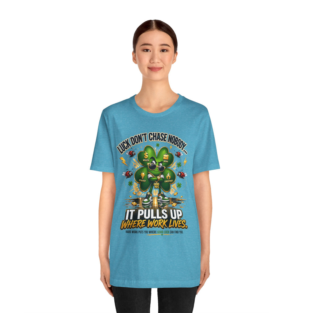 A young woman models the TimeWarp Drip Lucky Clover "Pulls Up Lives" Graphic T-Shirt (S-3XL), featuring a smiling four-leaf clover, gold coins, and the quote: "Luck don’t chase nobody—it pulls up where work lives," against a white background.