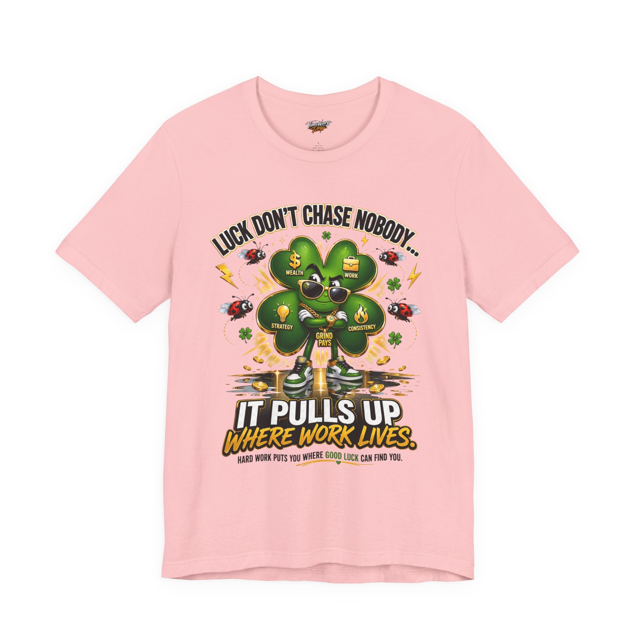 The Lucky Clover "Pulls Up Lives" Graphic T-Shirt by comes in pink (sizes S–3XL) and features a bold green four-leaf clover with the motto: Luck don’t chase nobody... It pulls up where work lives. Hard work brings good luck.