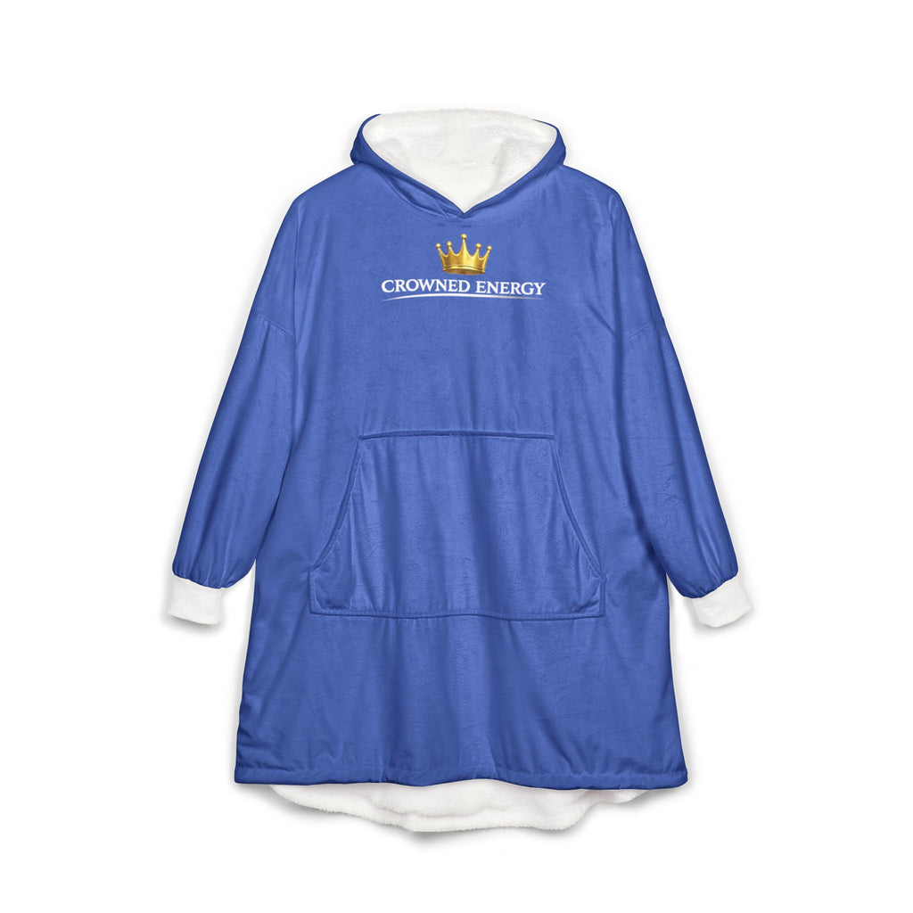 The "Crowned in Every Era" Royal Chess Graphic Hooded Blanket in royal blue features a soft white fleece lining, front pocket, and CROWNED ENERGY text with a gold crown graphic on the chest. One size fits most, perfect for lounging. Displayed on a white background.