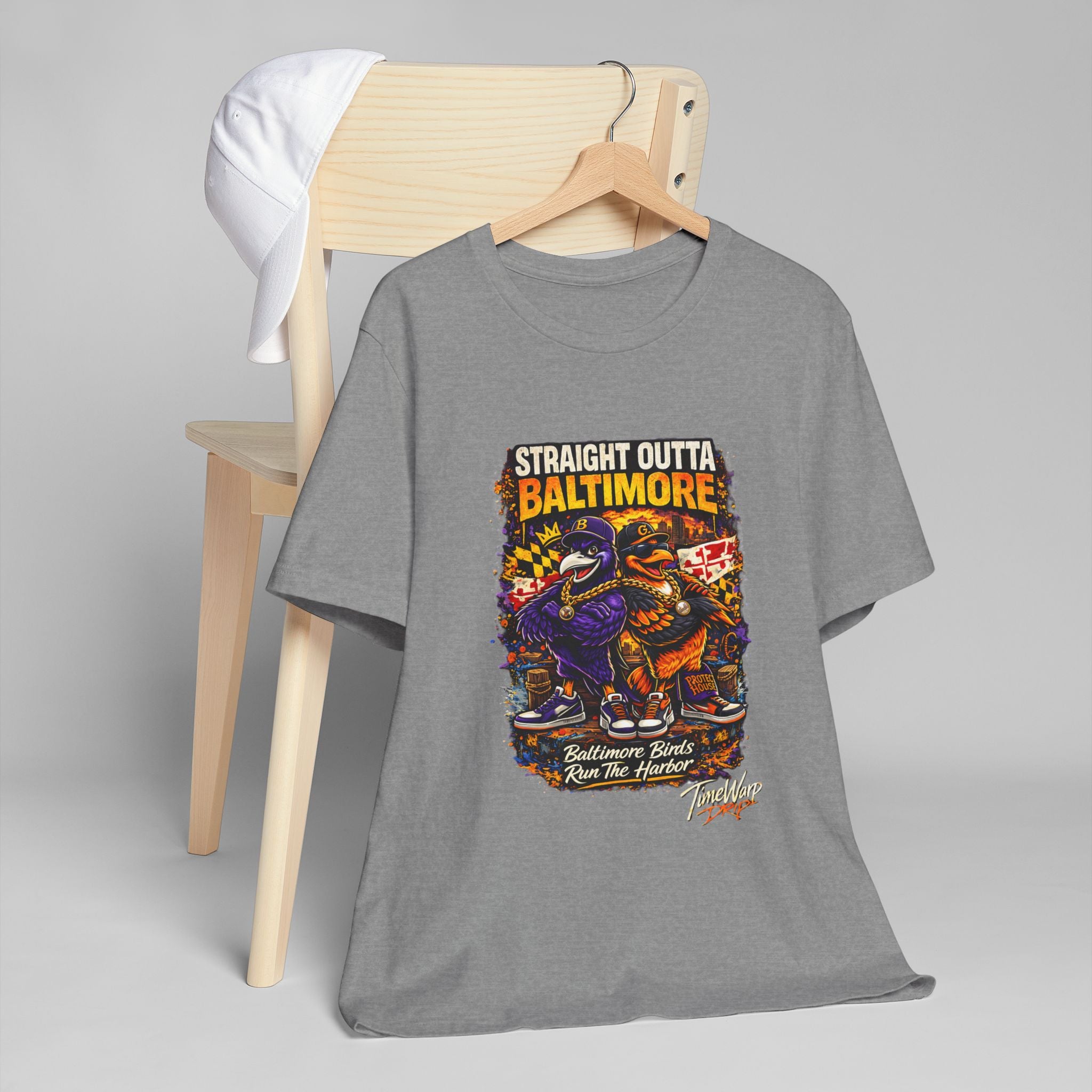 TimeWarp Drip Bold black Straight Outta Baltimore graphic tee with cool cartoon birds, street-styled on a chair, crowned by a crisp white cap. streetwear apparel