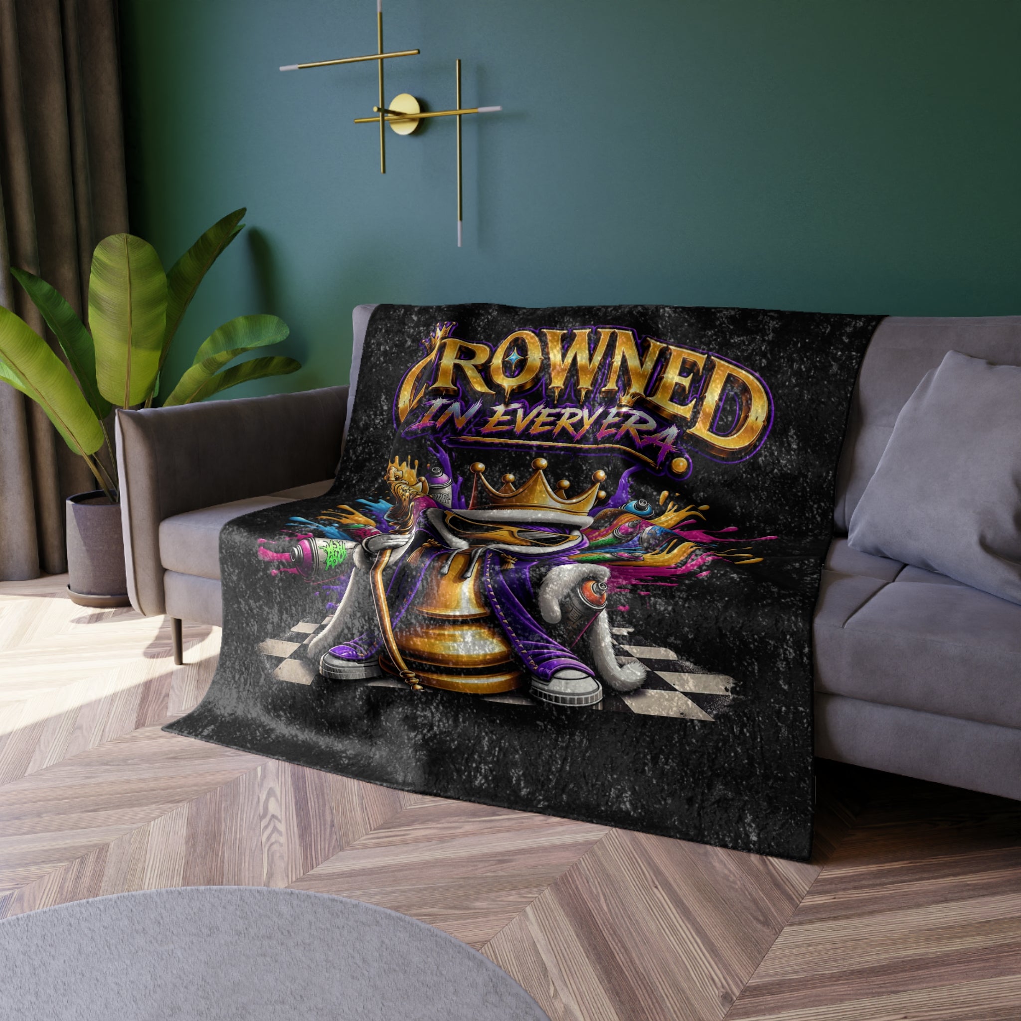 TimeWarp Drip “Crowned in Every Era” black crushed velvet blanket flexes bold street drip, iced out over a gray couch. 
