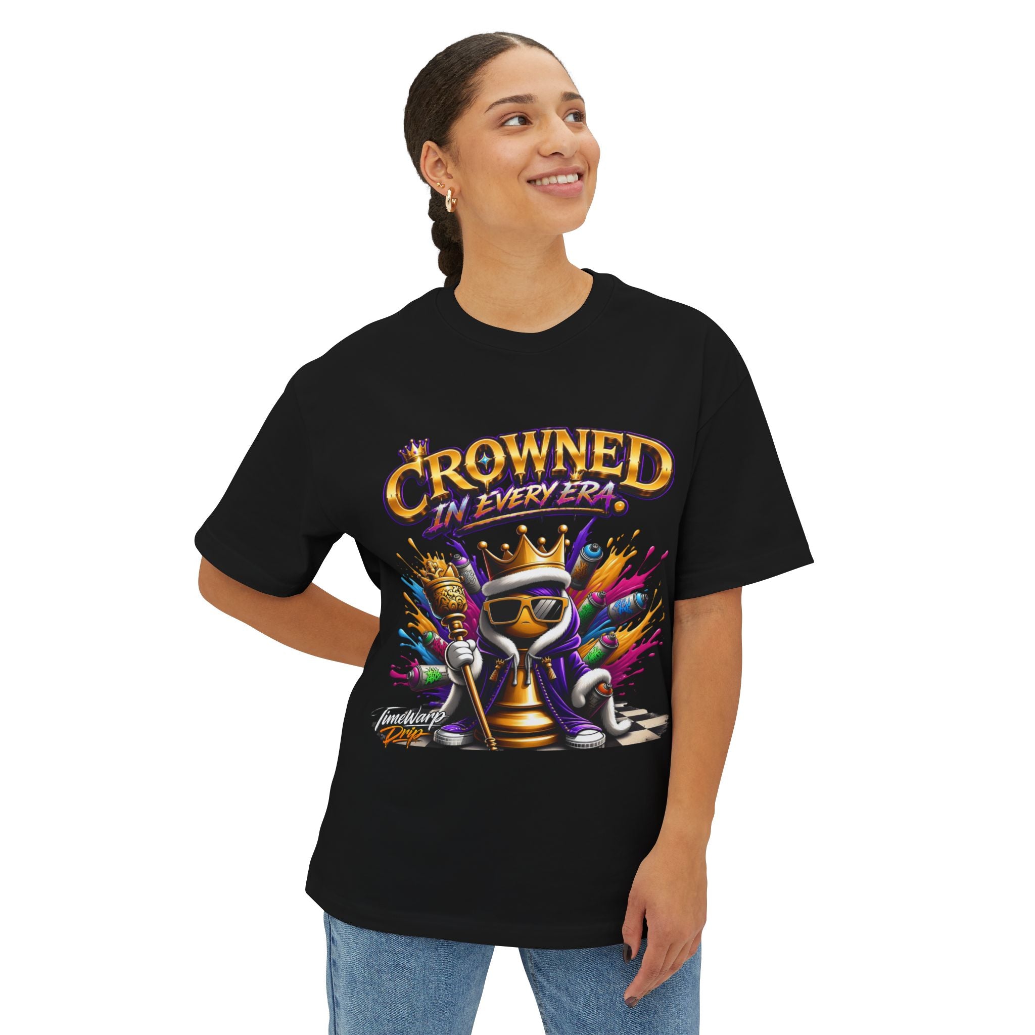 A woman smiles wearing the Crowned In Every Era - Unisex Oversized Boxy Tee, a relaxed fit black shirt in 100% airlume cotton, with a colorful crowned chess piece, sunglasses, paint splashes, and "CROWNED IN EVERY ERA" text.