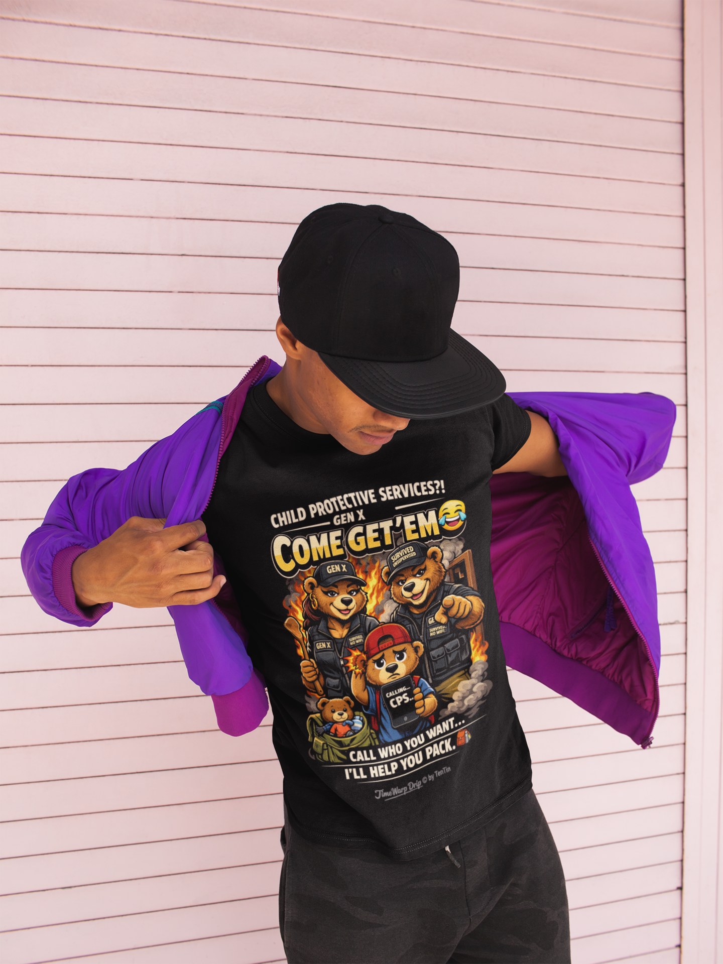 A person wearing a black cap, a purple jacket, and the Generation X Parenting "Come Get Em" Oversized Boxy T-Shirt by TimeWarp Drip stands in front of a pink striped wall, looking down while adjusting their jacket.