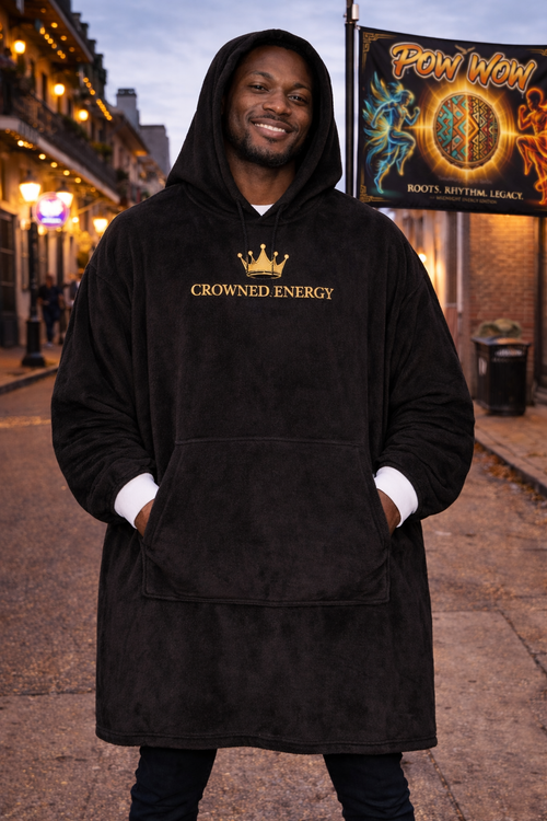 TimeWarp Drip Man rocks a bold black "Crowned in Every Era" hooded blanket by TimeWarp Drip, dripping streetwear swagger at dusk on the city block. streetwear apparel