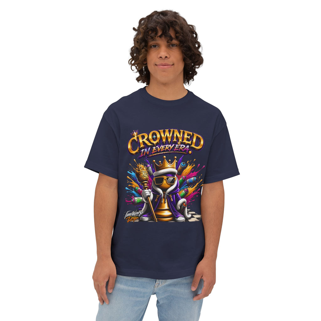 A person with curly hair wears the navy blue "Crowned In Every Era - Unisex Oversized Boxy Tee," featuring a colorful crowned chess piece and text, styled in a relaxed fit against a plain background.