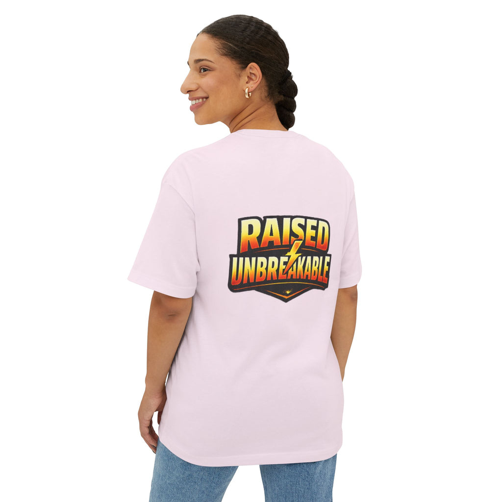 A woman with braided hair smiles while wearing the Generation X Parenting "Come Get Em" Oversized Boxy T-Shirt by TimeWarp Drip, a light pink, breathable cotton tee featuring bold, colorful RAISED UNBREAKABLE lettering on the back as she looks over her shoulder.