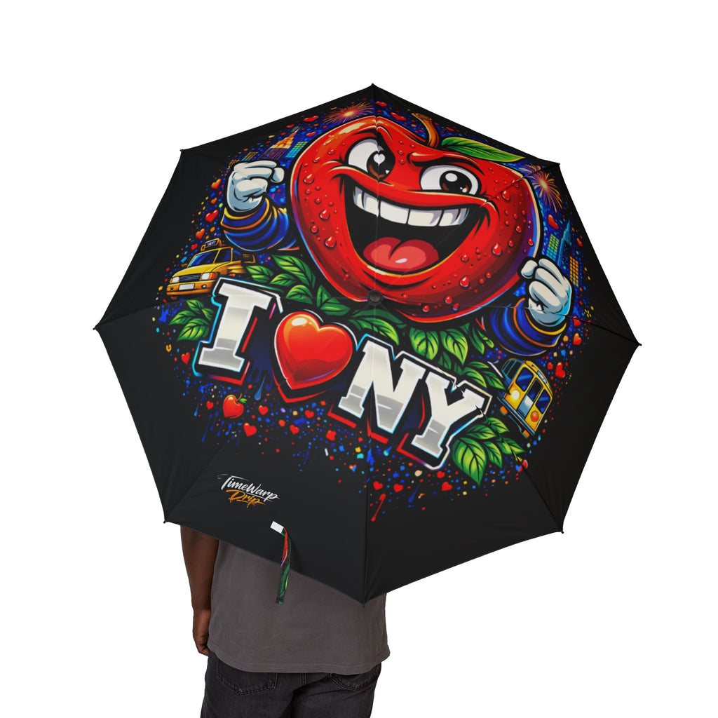 A person holds the TimeWarp Drip I Love NYC foldable umbrella—a black, semi-automatic rain umbrella with a colorful graffiti-style design, cartoon red apple character, and bold "I ❤️ NY" text plus yellow taxi illustrations.