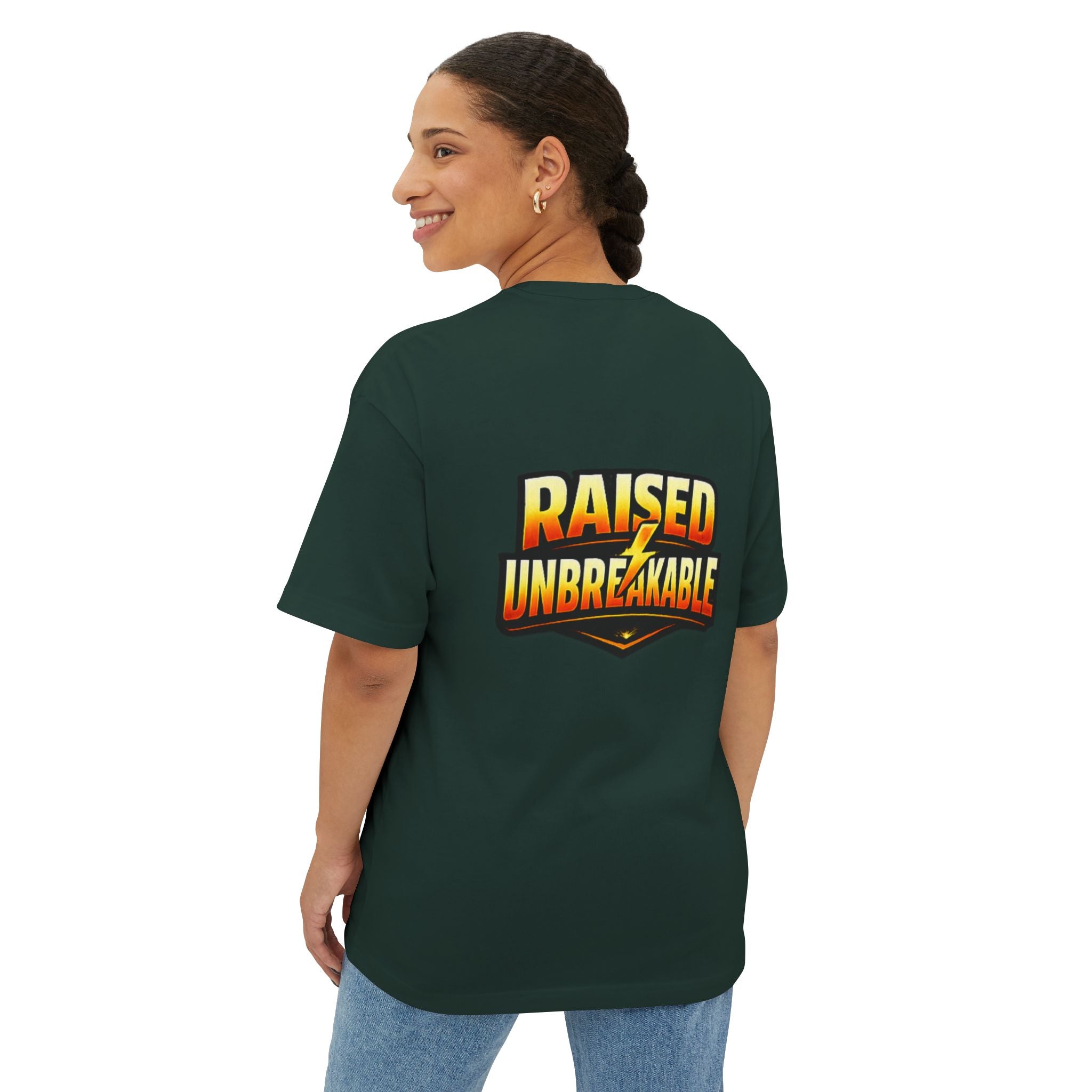 A smiling woman with braided hair models the TimeWarp Drip Generation X Parenting "Come Get Em" oversized boxy tee in dark green cotton, featuring bold, colorful text and a lightning bolt on the back. She pairs it with light blue jeans.