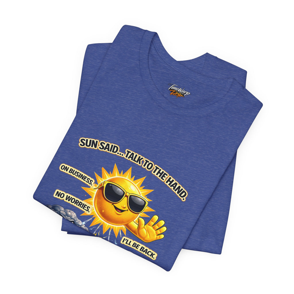 The Calm Energy Vibes T-Shirt by TimeWarp Drip features "I Run the Forecast" CEO Energy: a folded blue lightweight tee in soft Airlume cotton with a cartoon sun in sunglasses saying, “SUN SAID... TALK TO THE HAND. ON BUSINESS. NO WORRIES. I’LL BE BACK,” plus a smiling cloud.