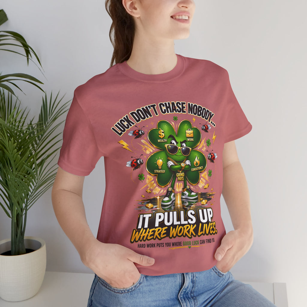 A smiling woman wears the TimeWarp Drip "Lucky Clover, Pulls Up Lives" Graphic T-Shirt (S-3XL), featuring a cartoon four-leaf clover made of dollar bills and coins, with the phrase: Luck don’t chase nobody… It pulls up where work lives.