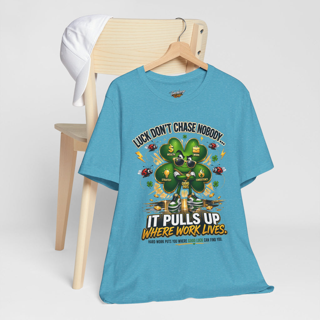 The TimeWarp Drip Lucky Clover "Pulls Up Lives" Graphic T-Shirt (S-3XL) features a four-leaf clover and reads: Luck don’t chase nobody—it pulls up where work lives. Hard work puts you where good luck can find you.