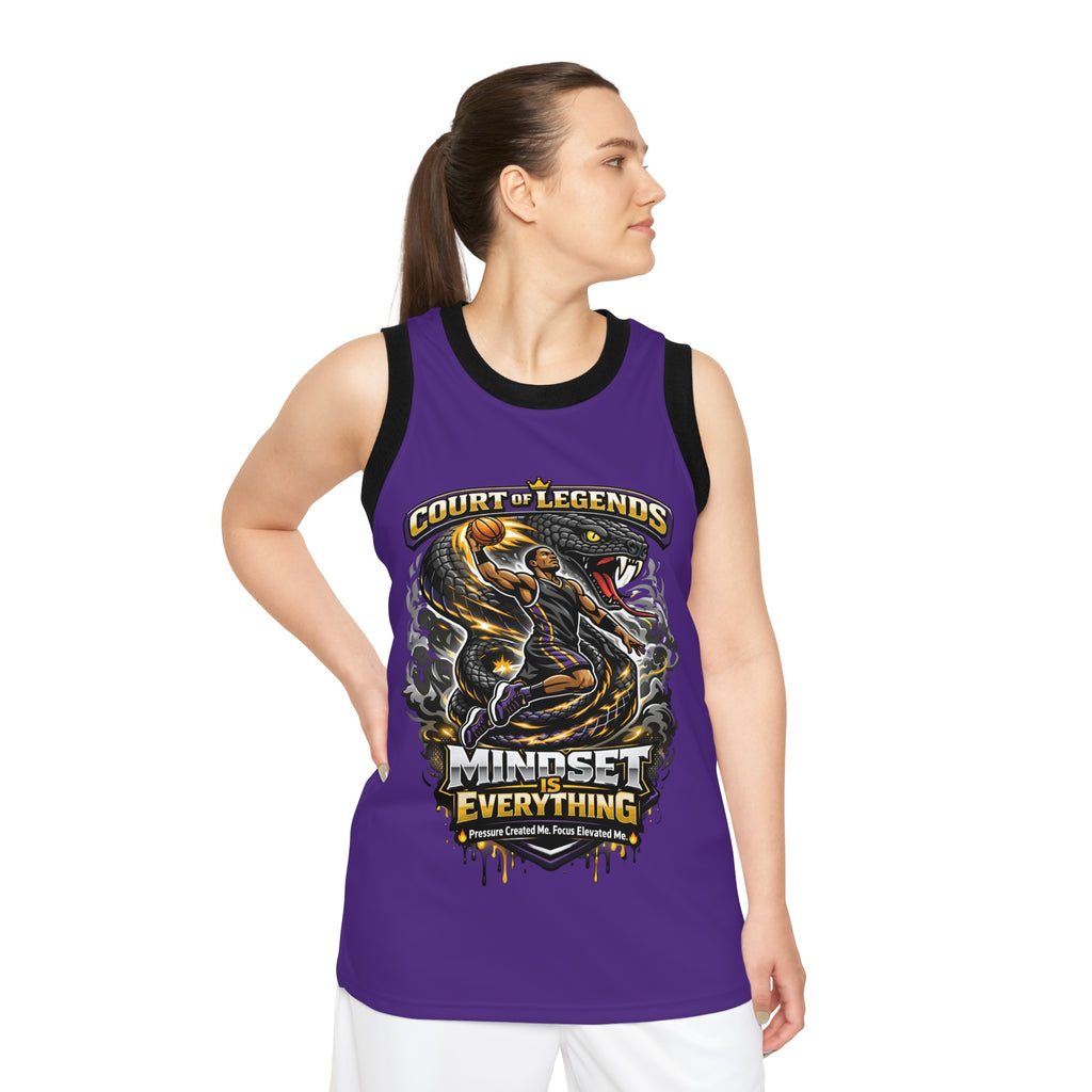 A woman in a Court of Legends (Purple) Basketball Jersey with a unisex fit, "Mindset is Everything" text, and an illustration of two players in action stands looking to her left.