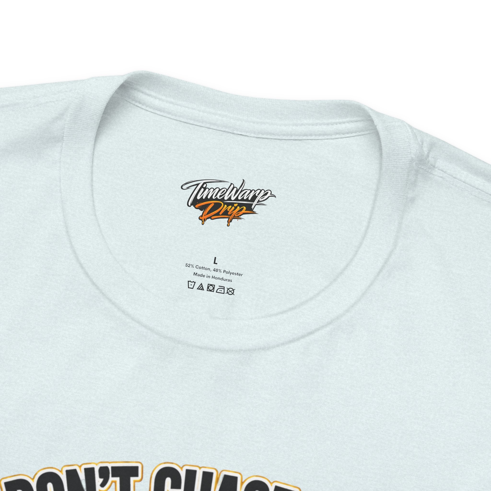 The Lucky Clover "Pulls Up Lives" Graphic T-Shirt by TimeWarp Drip comes in light colors, sizes S–3XL, with care instructions inside the collar and a bold “DON’T CHAS...” slogan on the front.