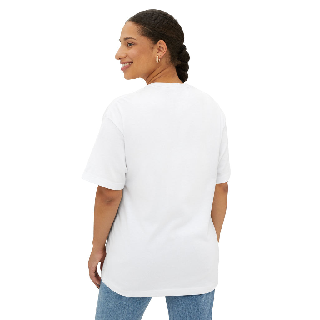 A woman with braided hair models the Crowned In Every Era Unisex Oversized Boxy Tee, a relaxed fit white short-sleeve shirt, styled with blue jeans. She stands facing away and smiles over her shoulder against a white background.