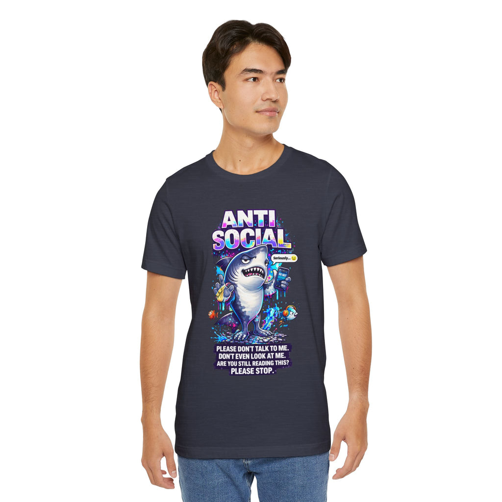A young man wears the Anti Social Shark T-Shirt — Funny Introvert Graphic Tee, featuring a cartoon shark, sea creatures, bold ANTI SOCIAL text, and a quirky message: Please don’t talk to me. Don’t even look at me. Are you still reading this? Please stop.