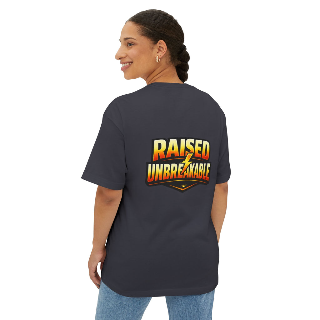 A smiling woman with braided hair wears the TimeWarp Drip Generation X Parenting "Come Get Em" oversized boxy tee. The breathable cotton shirt features “RAISED UNBREAKABLE” in bold, colorful letters on the back as she turns to show the design.