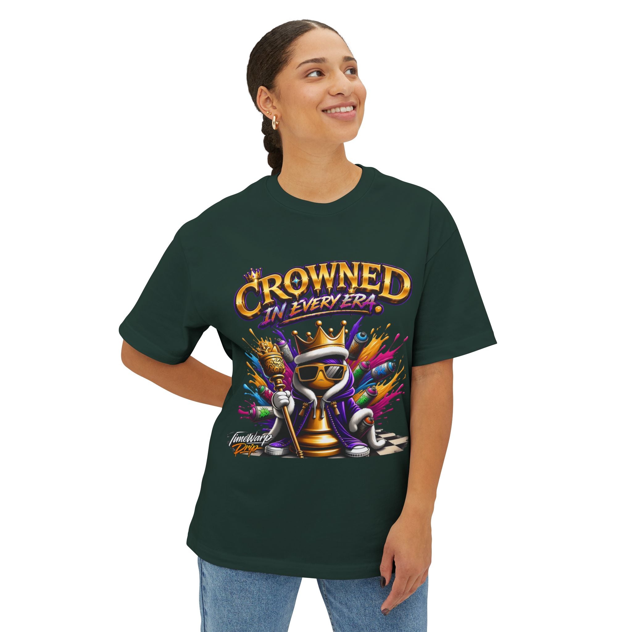 A smiling person wears the Crowned In Every Era - Unisex Oversized Boxy Tee, featuring a crowned chess piece with a scepter and “CROWNED IN EVERY ERA” text. Made from soft Airlume combed cotton for comfort and style.
