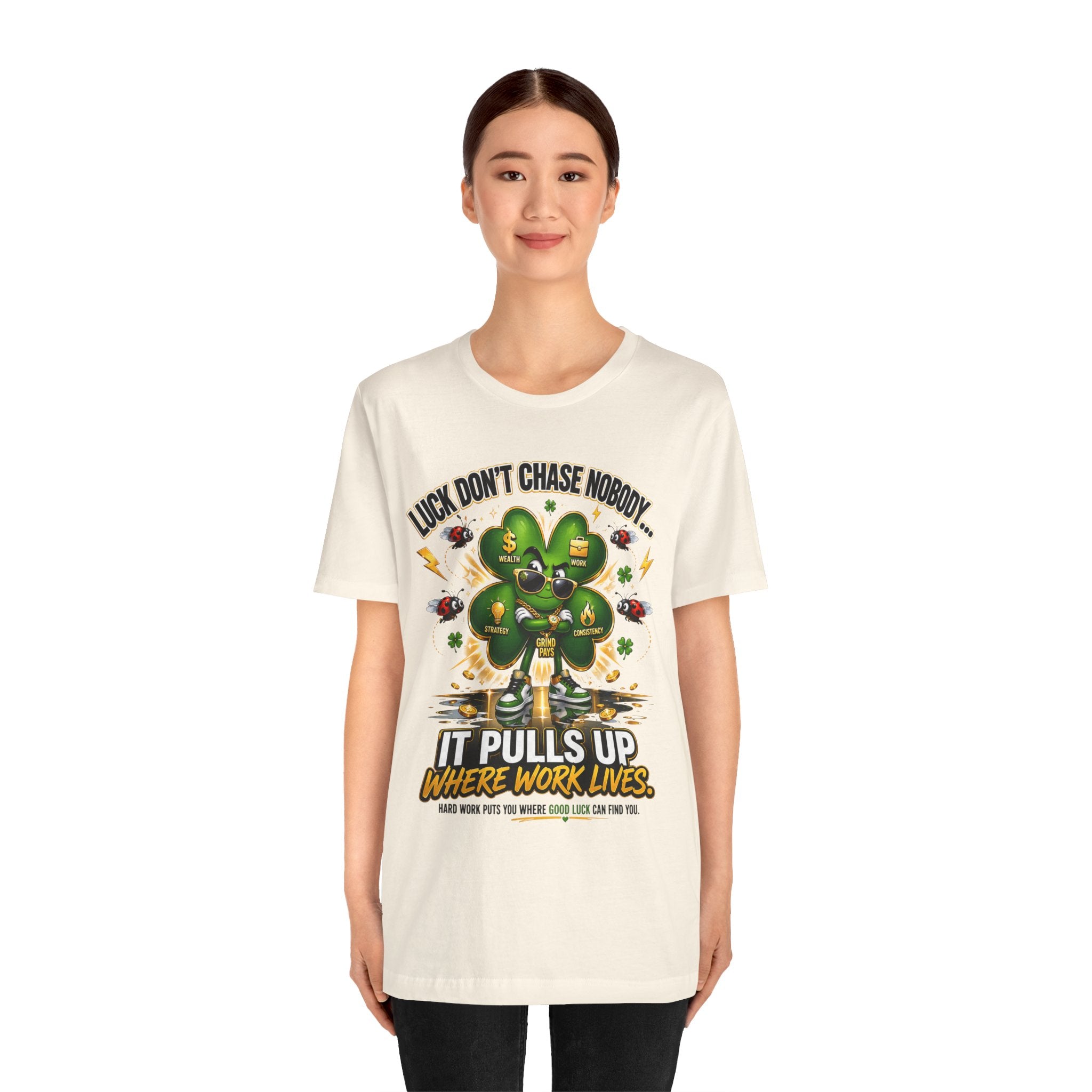 A woman faces forward, smiling softly in a Lucky Clover "Pulls Up Lives" Graphic T-Shirt (S–3XL), featuring a cartoon clover and the text "Luck, don’t chase nobody," set against a plain white background.
