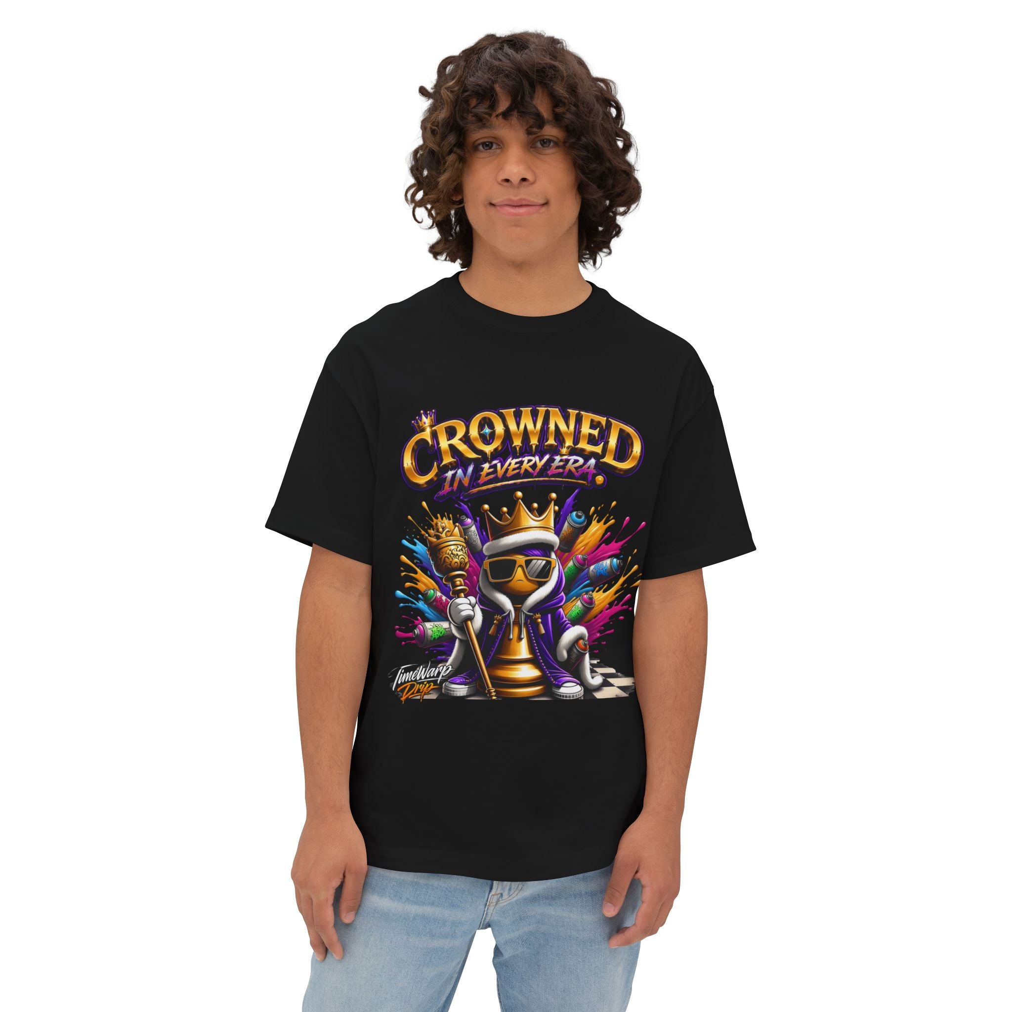 A young person with curly hair stands facing forward, wearing the Crowned In Every Era - Unisex Oversized Boxy Tee, which is black with a colorful crowned chess piece graphic and "Crowned in Every Era" text above it.