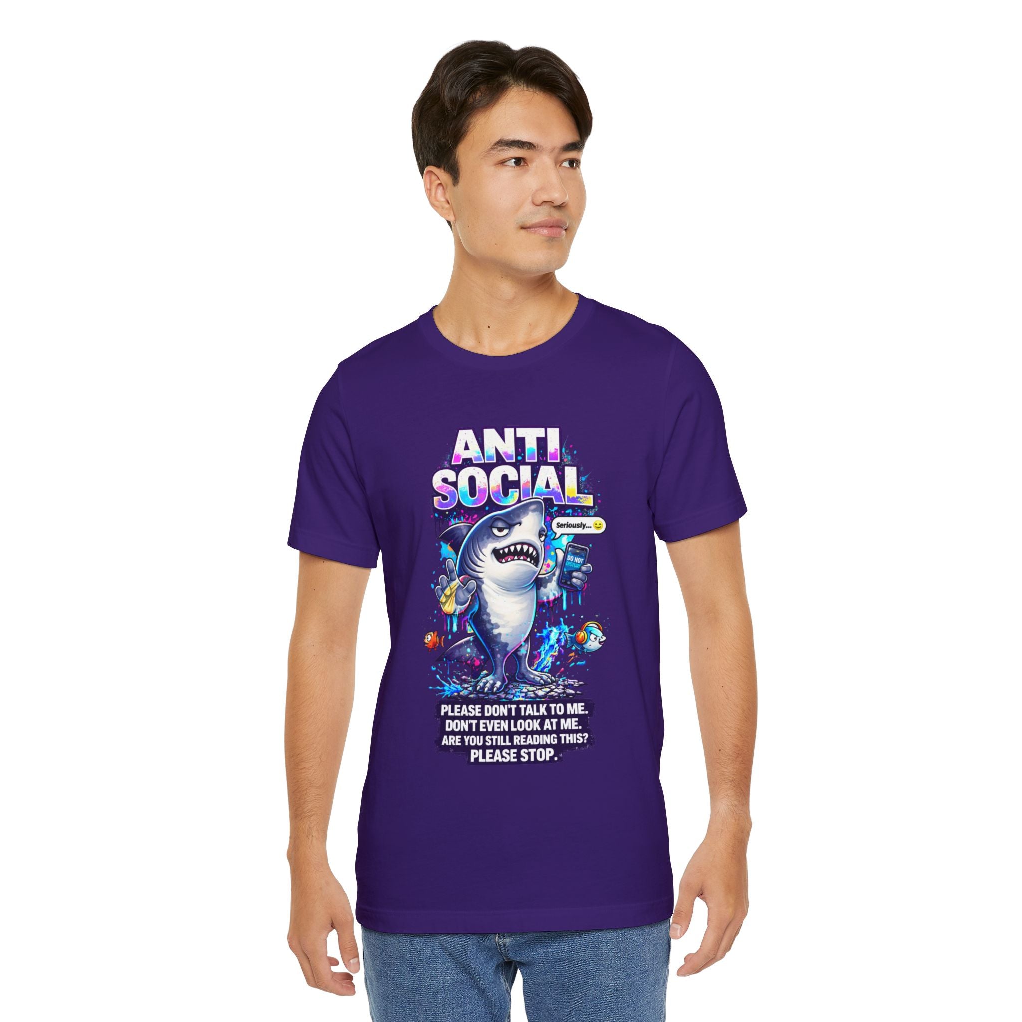 A young man wears an Anti Social Shark T-Shirt — Funny Introvert Graphic Tee, a purple unisex cotton shirt with a cartoon shark, vibrant graphics, and phrases like "Please don't talk to me," as he stands against a white background.