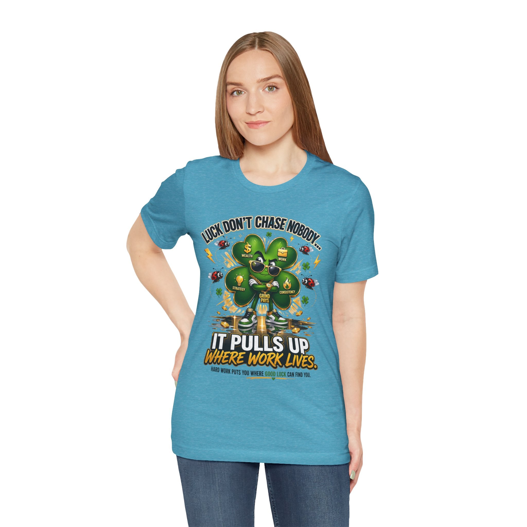 A woman with straight light brown hair wears the TimeWarp Drip Lucky Clover "Pulls Up Lives" Graphic T-Shirt (sizes S–3XL), featuring a clover, coins, and the text: "Lucky don't chase nobody, it pulls up where work lives." She stands facing forward.