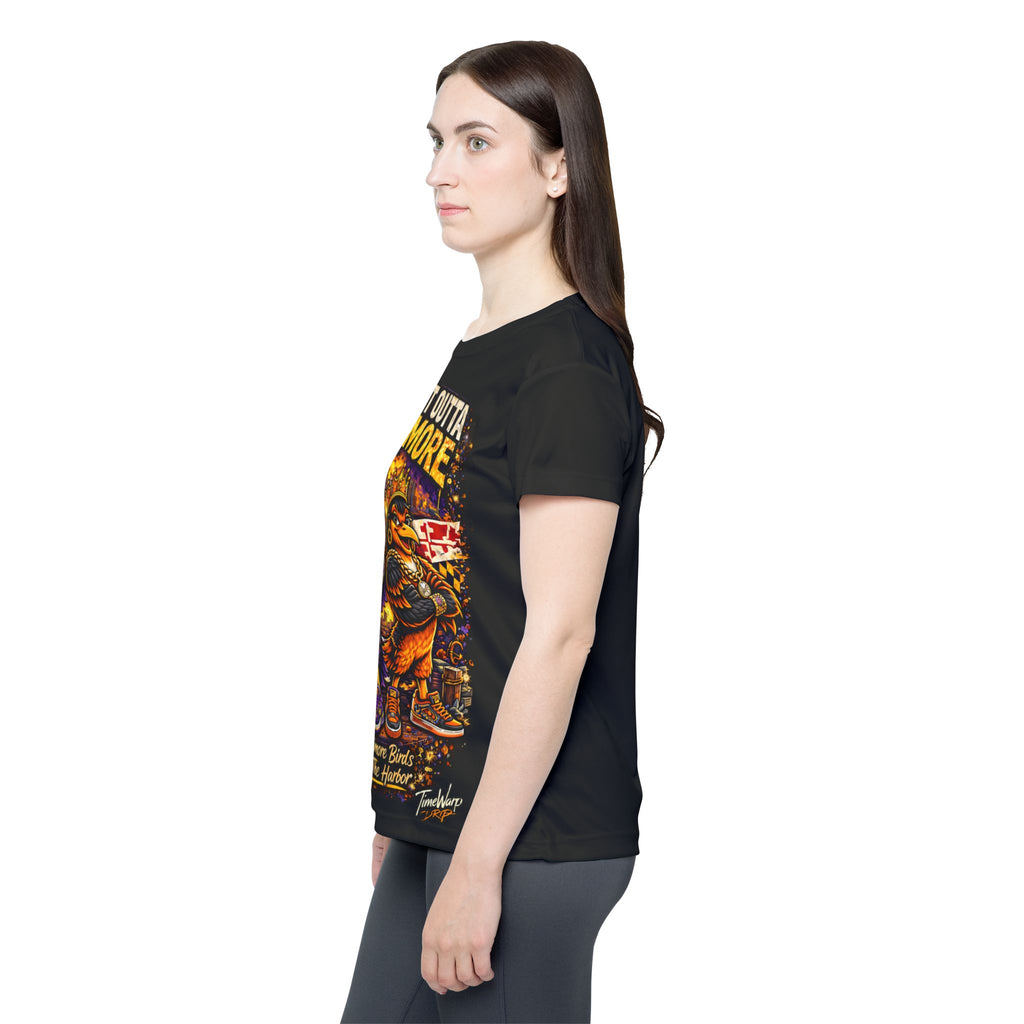 A woman with long brown hair, wearing a black Printify “Straight Outta Baltimore — Women’s Sports Jersey | Black Charm City Fan Tee,” and gray leggings stands in profile against a white background. The T-shirt features colorful Baltimore Birds artwork and text.