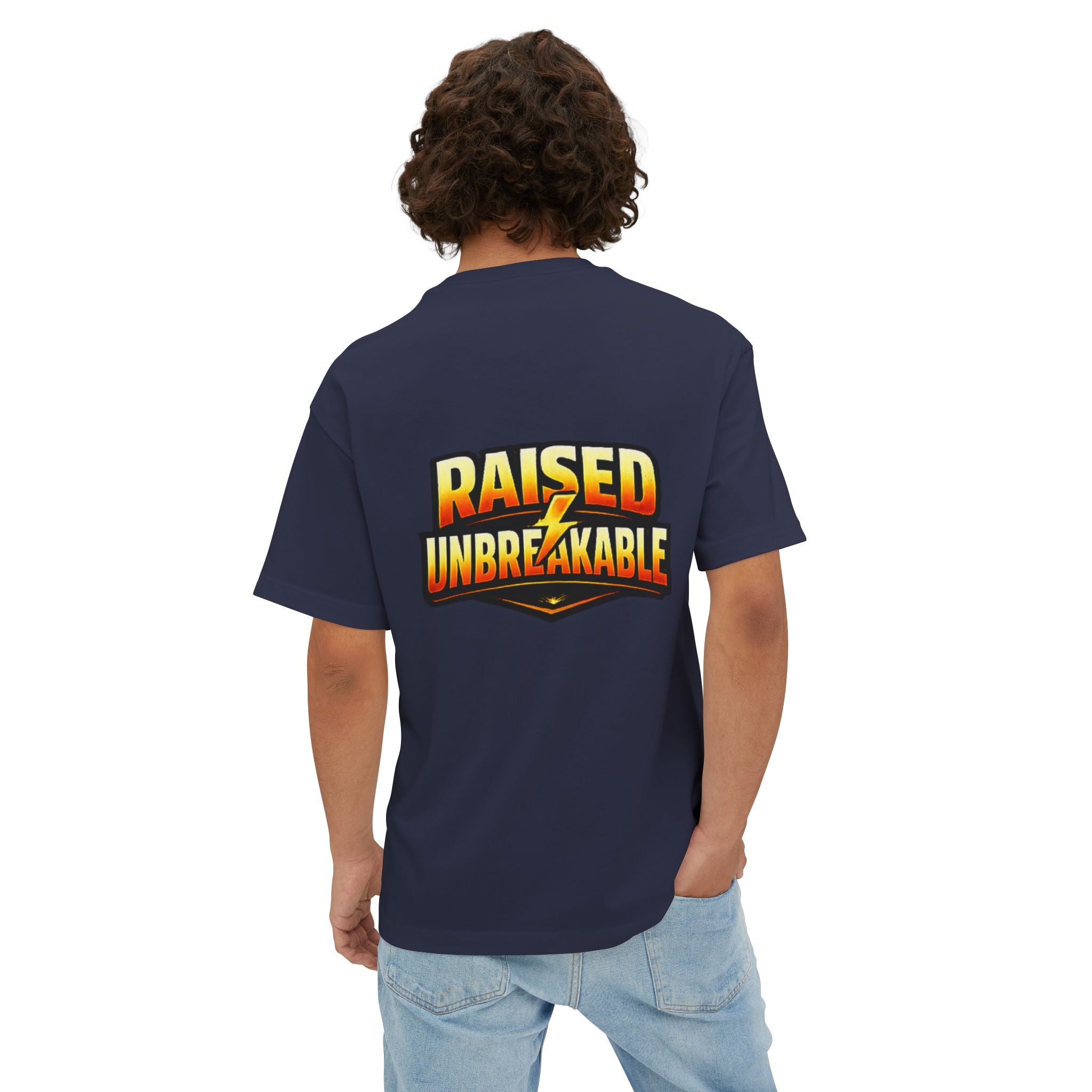 A person with curly hair wears the TimeWarp Drip Generation X Parenting "Come Get Em" oversized boxy tee in navy blue and light jeans, showing off bold, colorful “RAISED UNBREAKABLE” text with a lightning bolt on the breathable cotton back.
