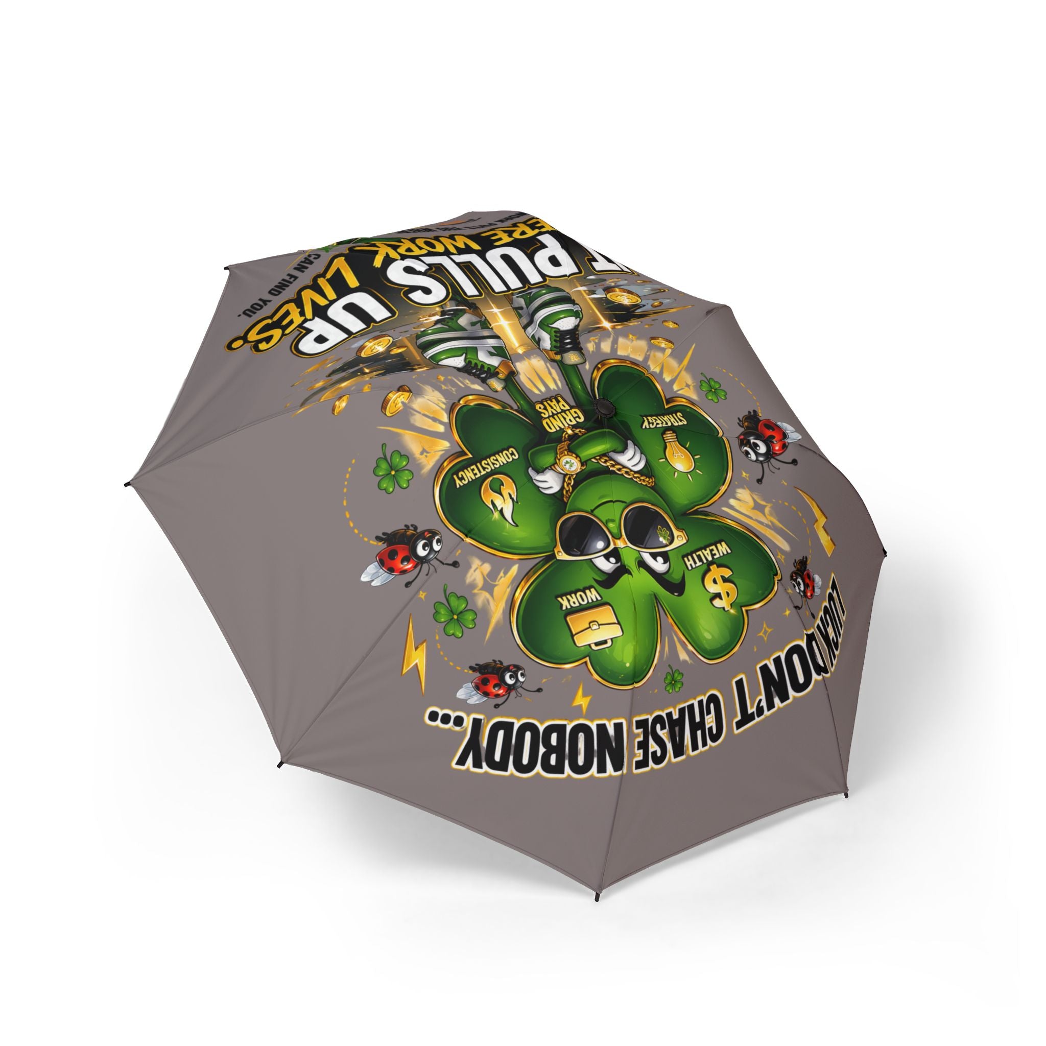 The Lucky Clover "Pulls Up Lives" Graphic Foldable Umbrella (Grey) features a green clover cartoon with paw prints, gold coins, sunglasses, and four small black and red dogs. Text: DON’T CHASE NOBODY... GET YOUR PAWS UP FOR LUCKY LIVES.
