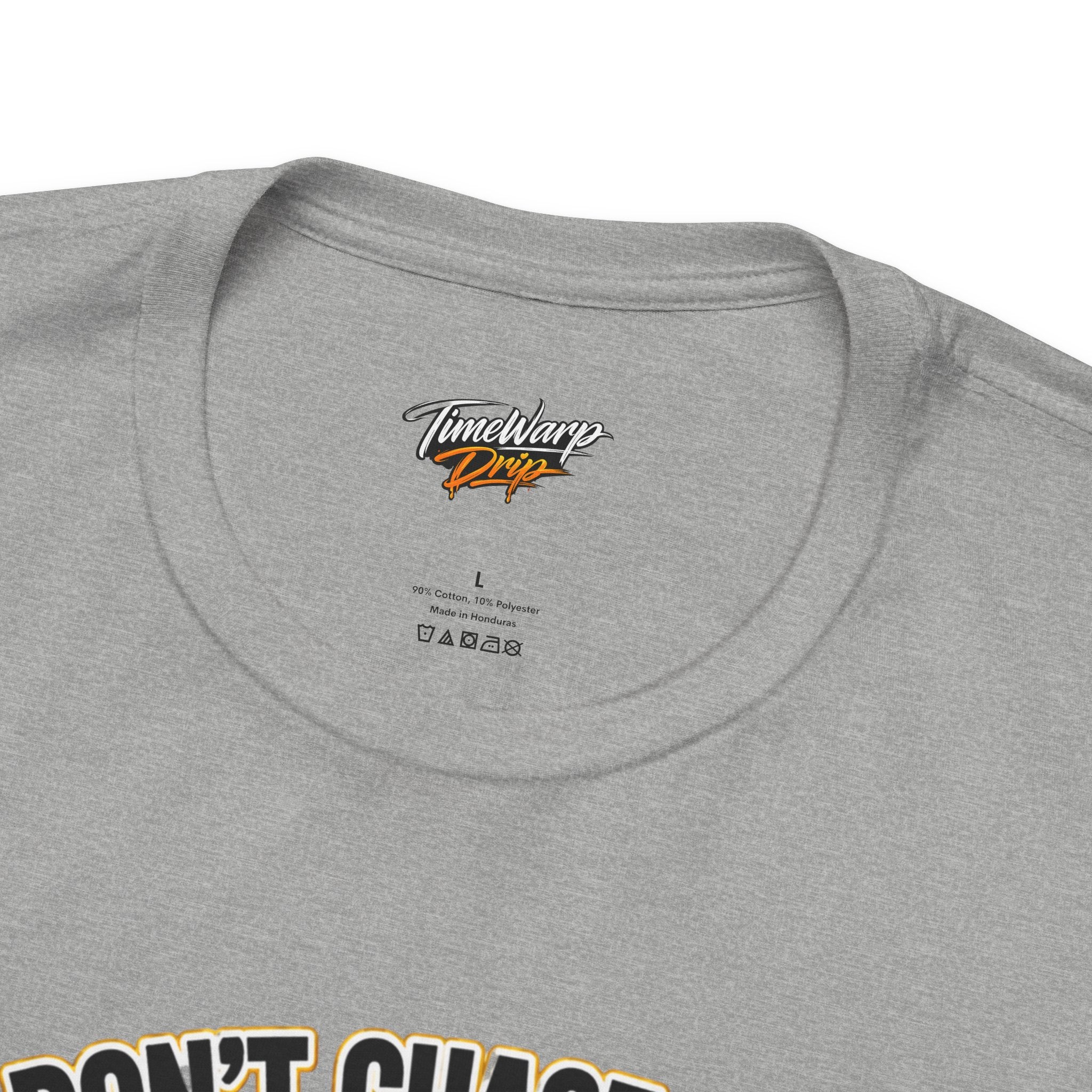 Close-up of a light gray TimeWarp Drip "Lucky Clover, Pulls Up Lives" Graphic T-Shirt with sizes S-3XL, laundry symbols, and Timewarp Drip printed inside the collar. Bold graphic text is partially visible at the bottom edge.